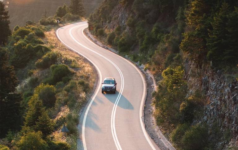 car crosses country road winding in twilight